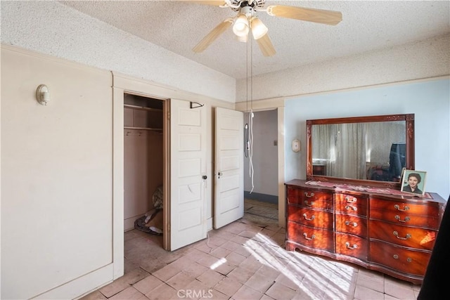 tiled bedroom with ceiling fan, a closet, and a textured ceiling