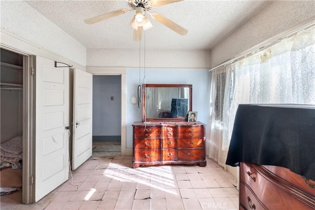 bedroom with ceiling fan, a textured ceiling, and light tile patterned floors