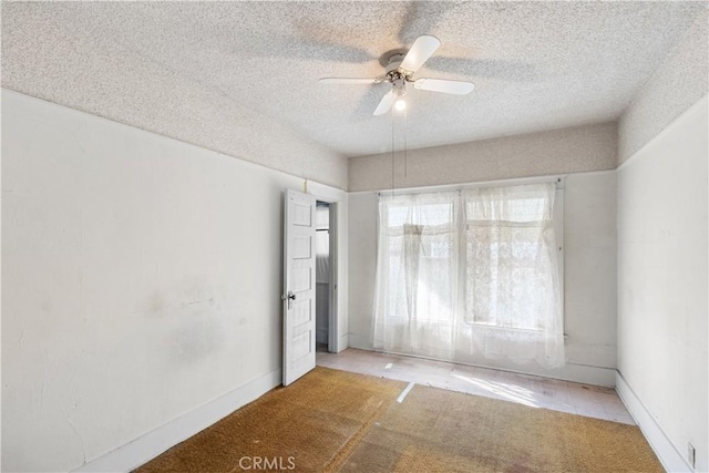 empty room with ceiling fan and a textured ceiling