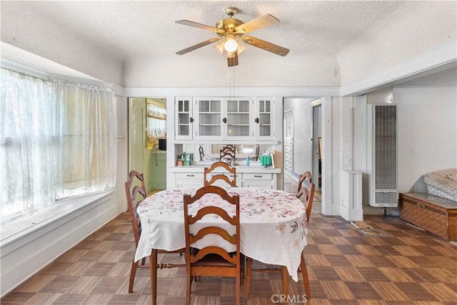 dining room with ceiling fan, dark parquet flooring, and a textured ceiling