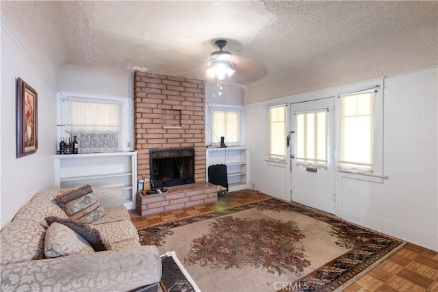 living room with ceiling fan, parquet flooring, a textured ceiling, and a brick fireplace