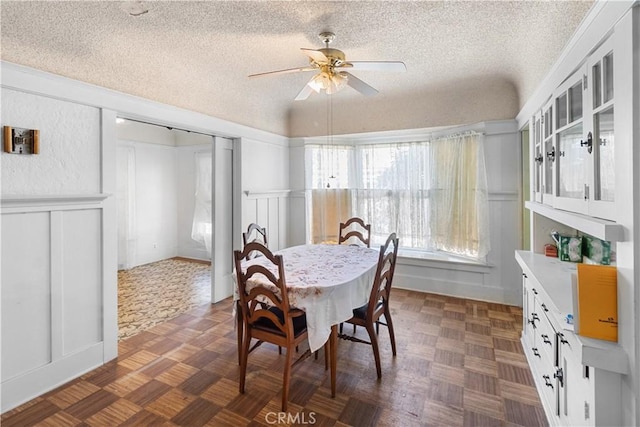 dining area with ceiling fan, dark parquet floors, and a textured ceiling