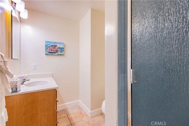 bathroom featuring toilet, vanity, baseboards, tile patterned floors, and a stall shower