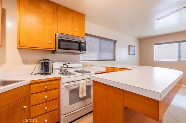 kitchen featuring light countertops, stainless steel microwave, white gas range, and a kitchen island