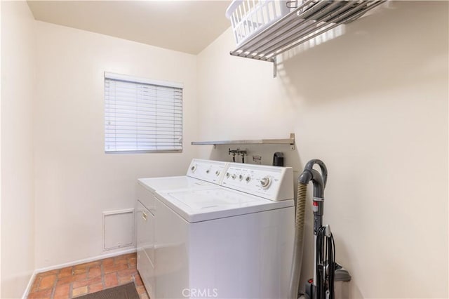 clothes washing area with brick floor, washing machine and dryer, and laundry area