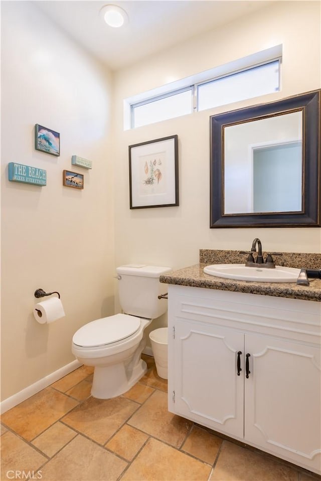 bathroom with toilet, tile patterned floors, baseboards, and vanity