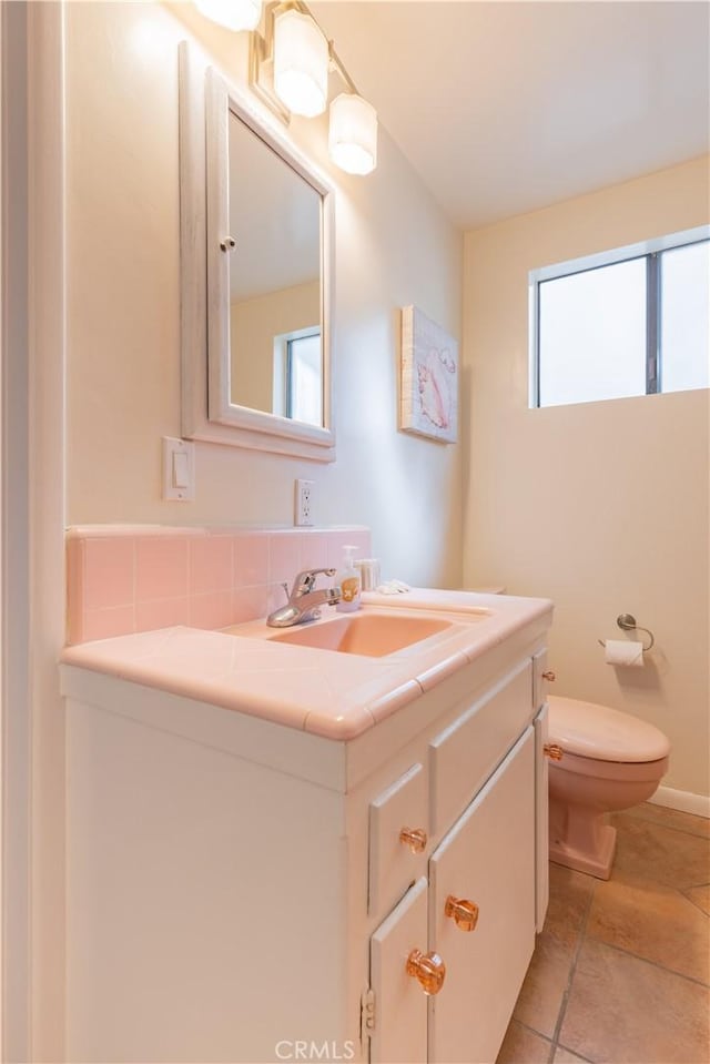 half bathroom with toilet, tile patterned flooring, and vanity