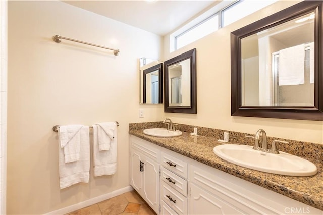 full bath featuring double vanity, tile patterned flooring, baseboards, and a sink