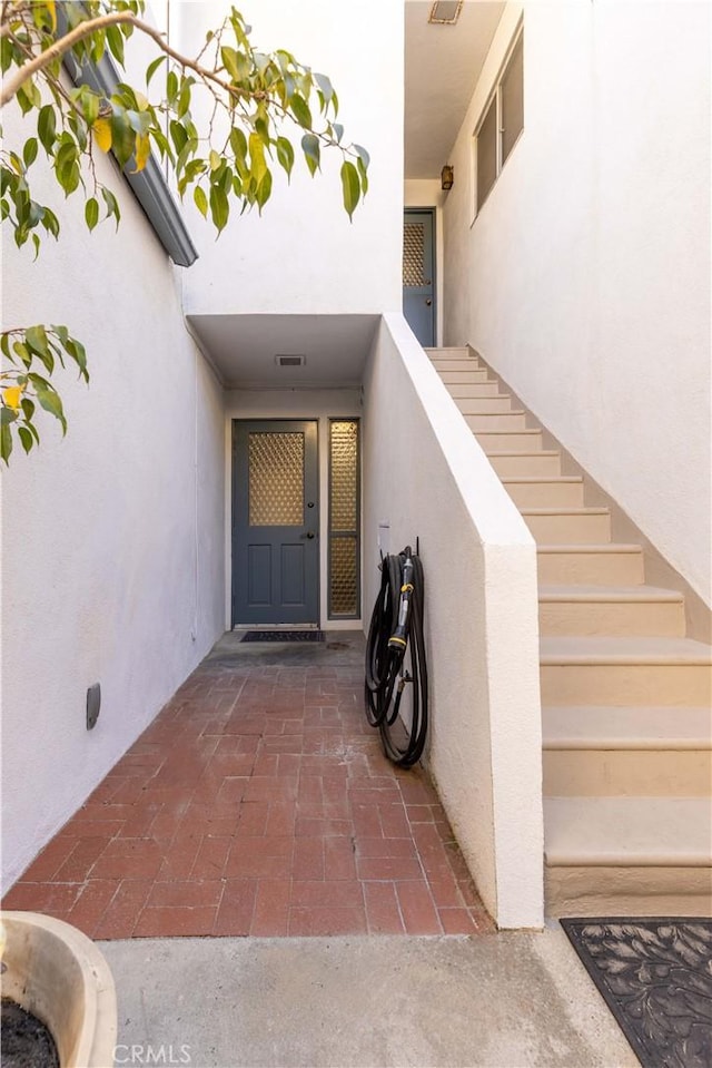 entrance to property with visible vents and stucco siding