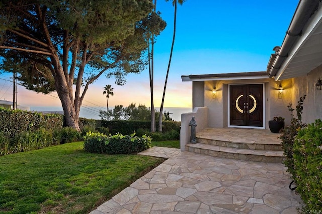 6130 Terryhill Dr, La Jolla, CA 92037 - exterior entry at dusk featuring a lawn and stucco siding