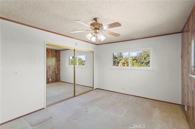 unfurnished bedroom with crown molding, light colored carpet, a closet, and a textured ceiling