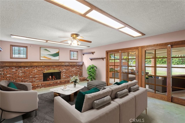 living room featuring ceiling fan, carpet flooring, a fireplace, and a textured ceiling