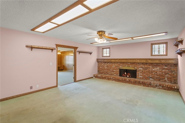 unfurnished living room with a brick fireplace, carpet floors, a textured ceiling, and ceiling fan