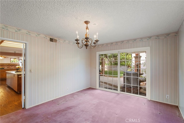 unfurnished dining area featuring carpet flooring, a chandelier, and a textured ceiling