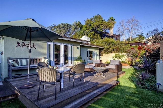 wooden terrace with an outdoor living space, a lawn, and french doors