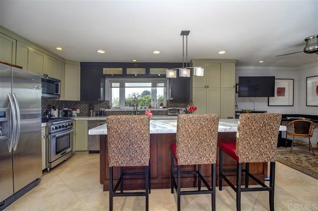 kitchen featuring pendant lighting, stainless steel appliances, tasteful backsplash, green cabinetry, and a kitchen island