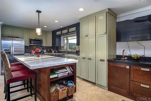 kitchen featuring sink, appliances with stainless steel finishes, hanging light fixtures, light stone counters, and a kitchen island