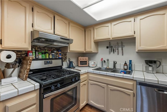 kitchen featuring appliances with stainless steel finishes, tasteful backsplash, sink, tile counters, and light brown cabinets