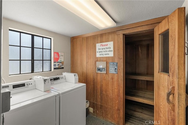 laundry area featuring washer and dryer, a textured ceiling, and wood walls