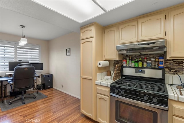 kitchen featuring stainless steel gas range oven, tasteful backsplash, tile counters, pendant lighting, and light hardwood / wood-style floors