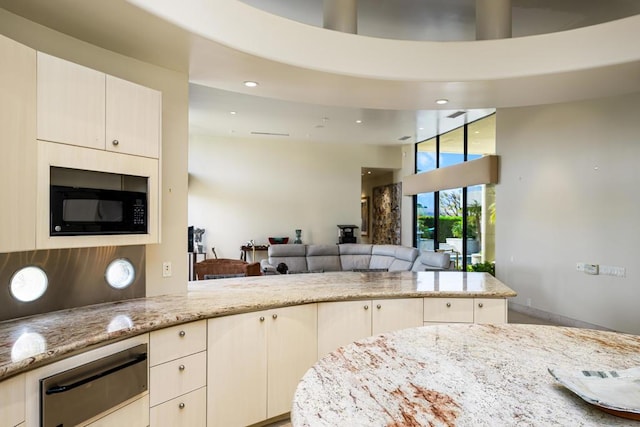 kitchen featuring light stone counters, kitchen peninsula, and a high ceiling