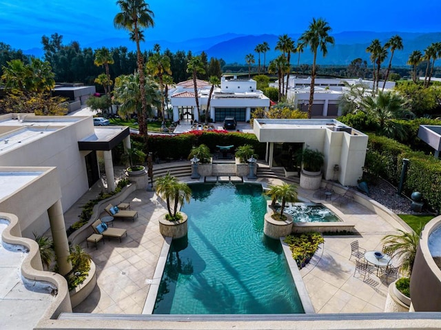 view of pool featuring a patio, a mountain view, and an in ground hot tub