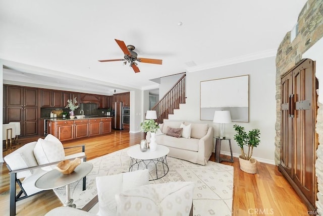 living room featuring ornamental molding, light hardwood / wood-style floors, and ceiling fan