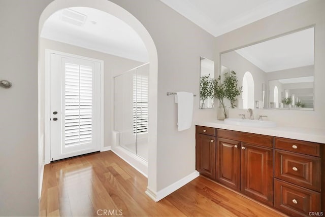 bathroom with vanity, hardwood / wood-style flooring, a shower with door, and crown molding