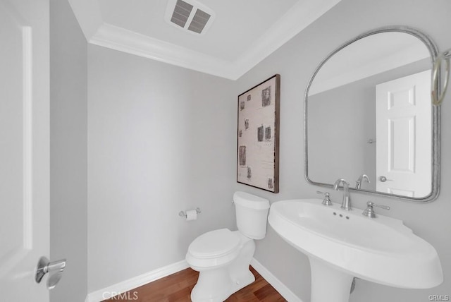 bathroom with hardwood / wood-style flooring, crown molding, sink, and toilet