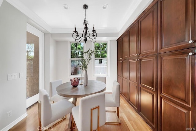 dining space featuring crown molding, an inviting chandelier, and light wood-type flooring