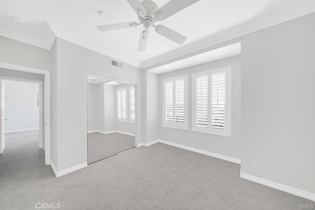 unfurnished bedroom with crown molding, carpet floors, ceiling fan, and a closet