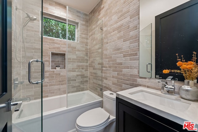 full bathroom featuring vanity, combined bath / shower with glass door, and toilet