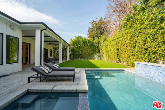 view of swimming pool with a yard, ceiling fan, and a patio area