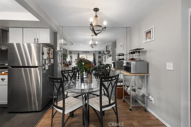 dining space with dark hardwood / wood-style flooring and a notable chandelier