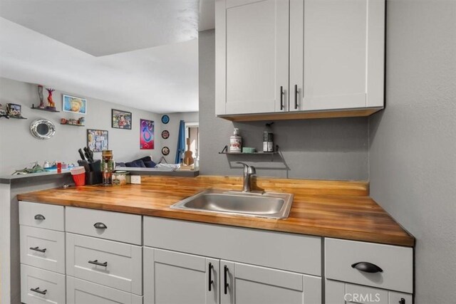 bar featuring white cabinetry, sink, and butcher block countertops