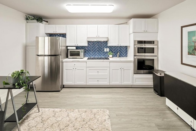 kitchen with white cabinetry, light wood-type flooring, tasteful backsplash, and appliances with stainless steel finishes