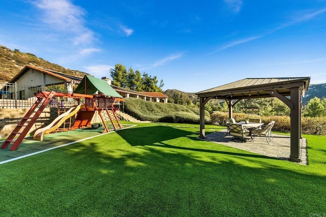 view of playground featuring a mountain view, a gazebo, a patio area, and a lawn