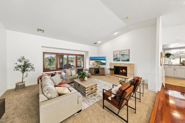 living room with lofted ceiling, a fireplace, and light hardwood / wood-style floors