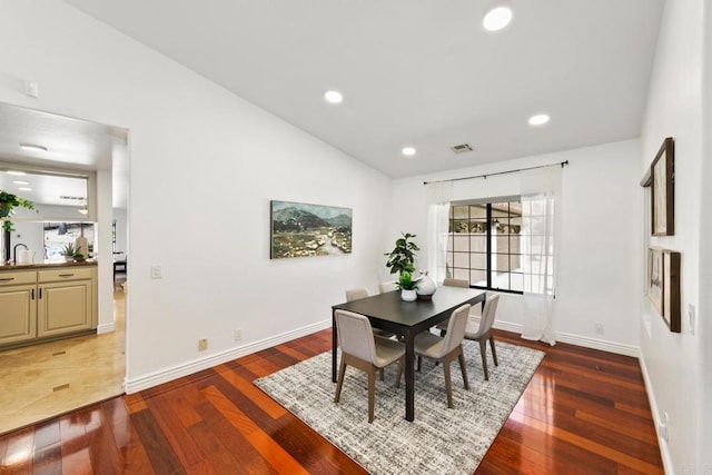 dining area featuring lofted ceiling, sink, and dark wood-type flooring