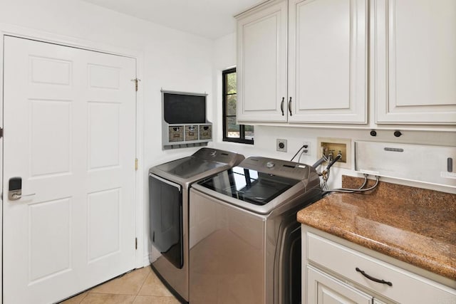 clothes washing area with light tile patterned floors, washer and clothes dryer, and cabinets