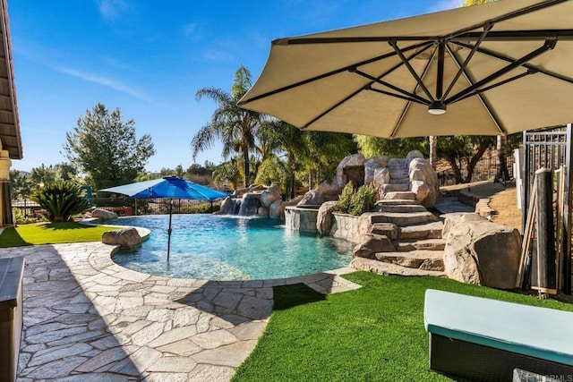 view of swimming pool with a patio, pool water feature, and a lawn