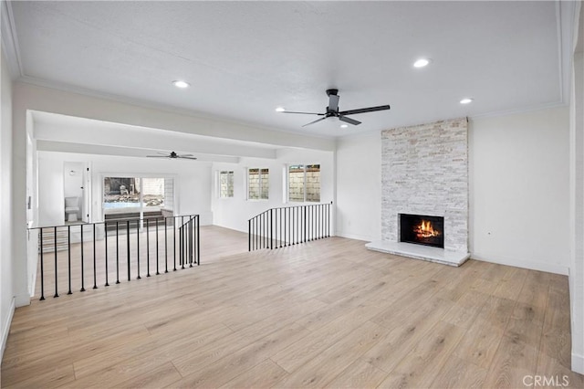 unfurnished living room featuring crown molding, ceiling fan, a fireplace, and light hardwood / wood-style flooring