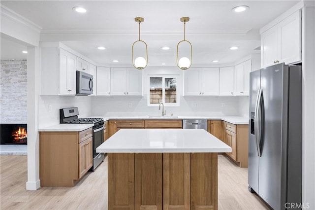 kitchen featuring pendant lighting, sink, stainless steel appliances, white cabinets, and a kitchen island