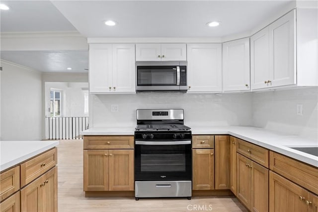 kitchen with stainless steel appliances, white cabinetry, and light wood-type flooring