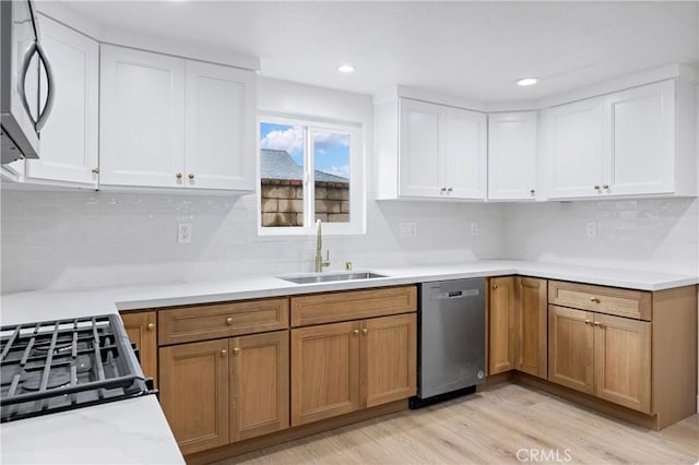 kitchen with sink, light hardwood / wood-style floors, white cabinets, and appliances with stainless steel finishes