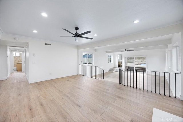 empty room with crown molding, plenty of natural light, and light hardwood / wood-style floors