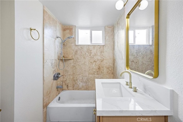 bathroom featuring tiled shower / bath and vanity