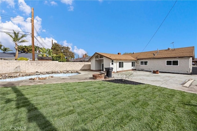 back of property with a fire pit, a lawn, and a patio