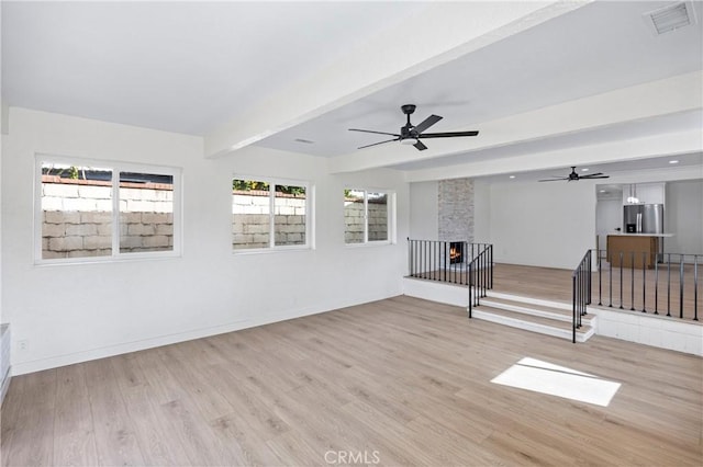 empty room featuring ceiling fan, beam ceiling, and light hardwood / wood-style flooring