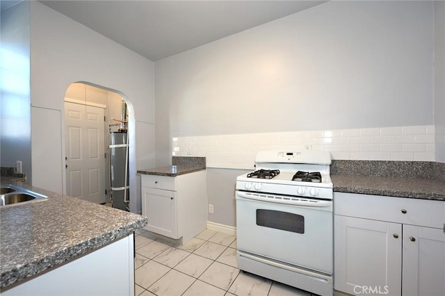 kitchen featuring white cabinetry, white gas range, tasteful backsplash, and refrigerator